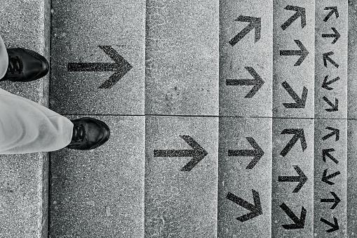A woman stands on a staircase and has to decide which way she wants to go