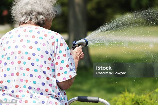 Mujer Mayor Y Pulverización De Agua Con Manguera De Jardín Foto de stock y más banco de imágenes de 80-89 años