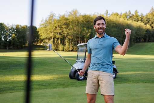 Golfer hitting golf shot with club on course while on summer vacation