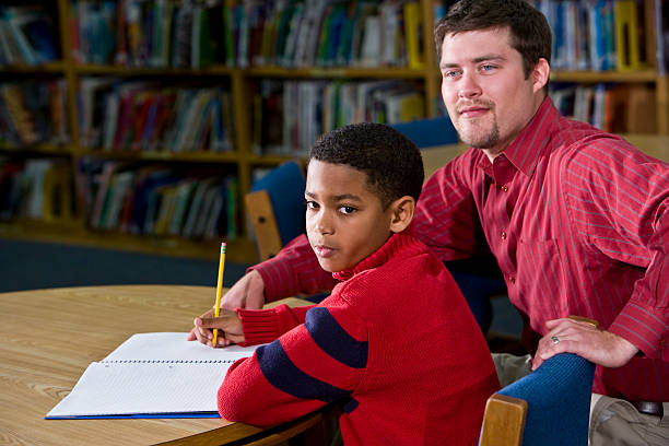 istock Teacher helping African American student in school library 184287757