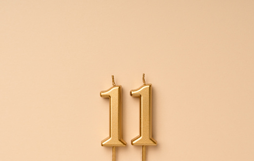 11 years celebration festive background made with golden candles in the form of number eleven. Universal holiday banner with copy space.