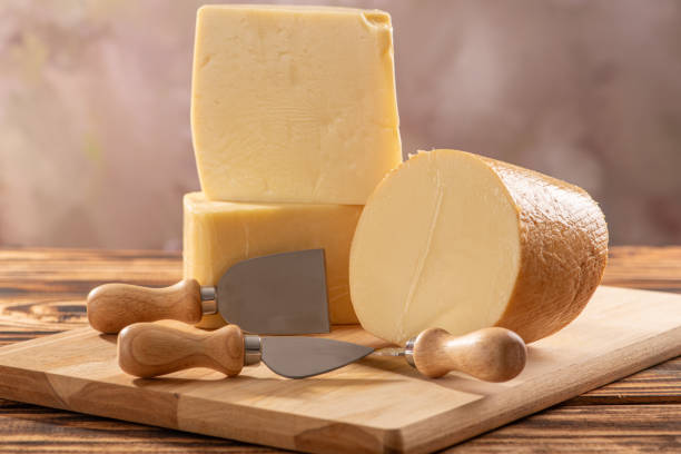 istock Cheeses, beautiful pieces of cheese and accessories placed on rustic wood, light background, selective focus. 1842879461