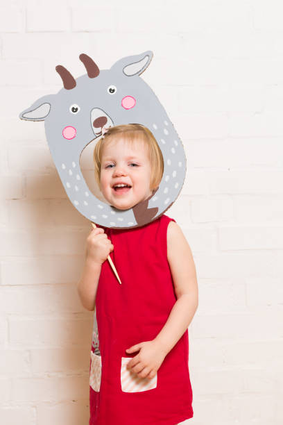 istock Little girls holding goat mask on white background 1842880202