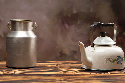 Coffee table, a kettle and a can of milk on a rustic table, selective focus.