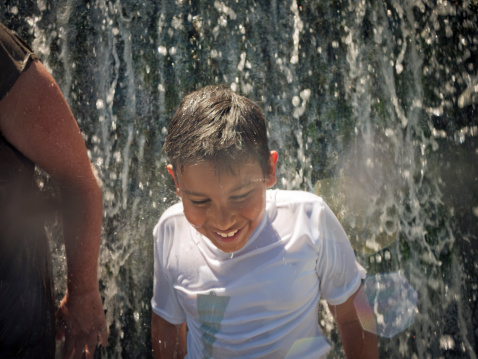 Young boy having fun under a waterfall.