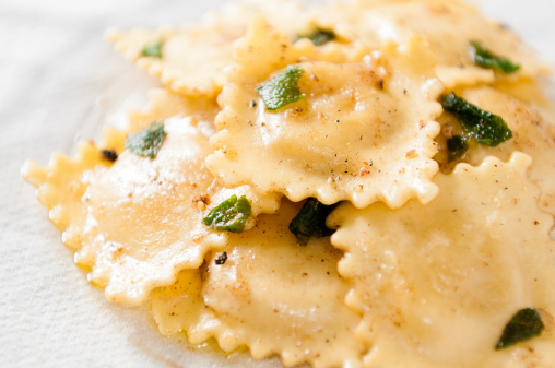 A plate full of cheese ravioli tossed with a brown butter sage sauce.