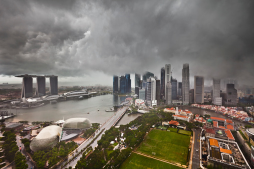 Thunderstorm with heavy dark clouds and rain over the skyline of Singapore. Falling rain and some grain are visible.