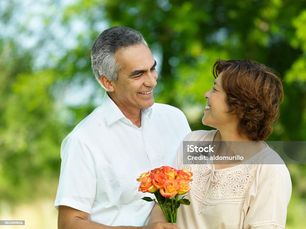 Amoroso hombre maduro dando flores - Foto de stock de 50-59 años libre de derechos