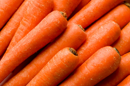 large orange carrot fruits on a wooden background