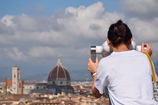 Woman is looking through scenic binoculars at Duomo Cathedral of Santa Maria del Fiore