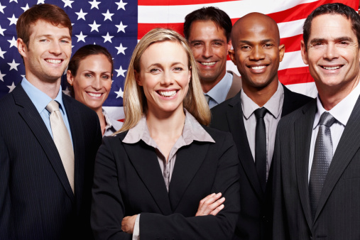 Portrait of enthusiastic business people smiling with an American flag in background