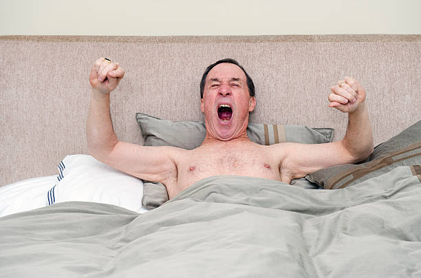 istock Sleepy Senior Man Yawning and Stretching in Bed 184290714
