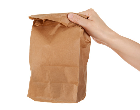 Woman's hand holding or giving a brown paper lunch bag. Studio isolated on a white background.Please also see: