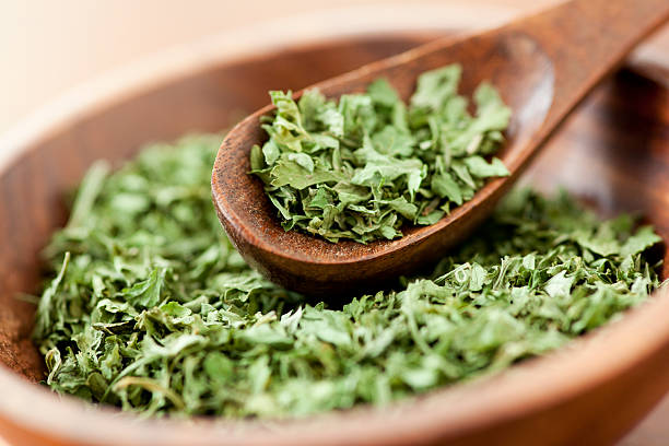 Parsley Dried parsley flakes along in a wooden bowl with a wooden spice spoon. parsley stock pictures, royalty-free photos & images