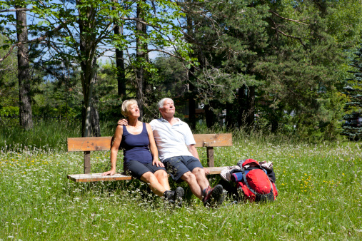 Senior couple relaxing on bench in blooming meadow