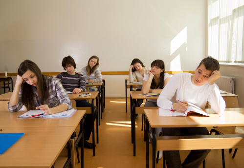 Confident student writing exam in classroom at high school