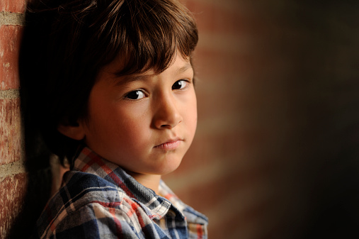 upset boy leaning against a brick wall