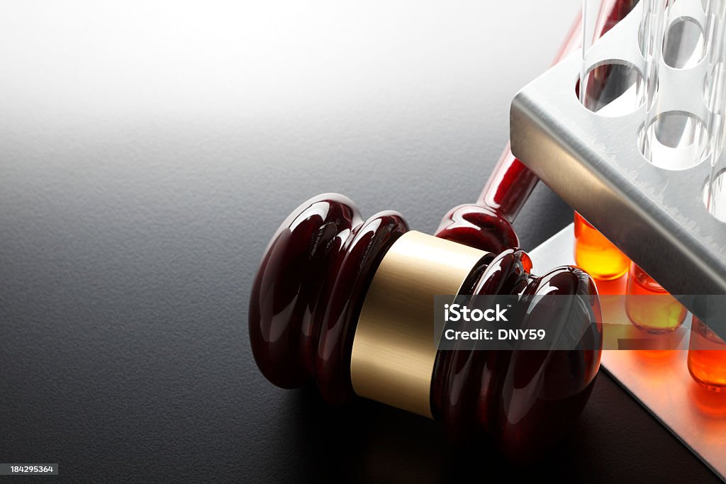 Gavel next to test tube rack on dark gray background A gavel and a rack of test tubes illustrating the concept of the law and scientific research or forensics and the law Morality Stock Photo