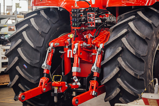 Rear view of modern agricultural tractor in hangar. Hydraulic hitch. Hydraulic lifting frame. Rear mechanism for attaching trailed equipment