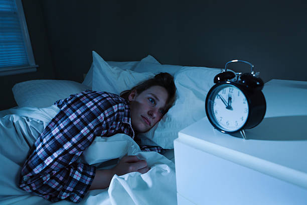 istock Sleepless Young Woman with Insomnia in Bed, Watching Alarm Clock 184296608