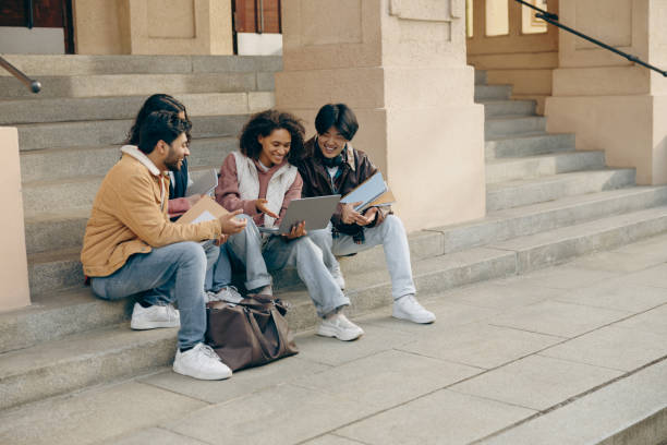 istock Cheerful students with laptop is studying outdoors sitting near university. Education concept 1842982783