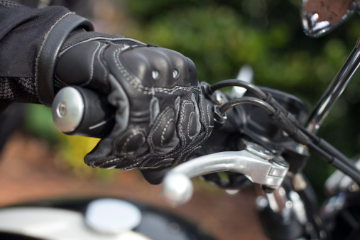 Gloved hand on the throttle grip of a motorbike