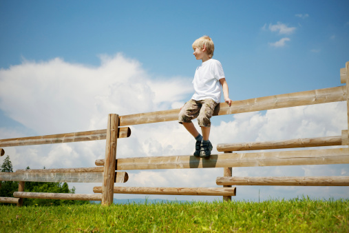 Boy sitting on a fence enjoying a view