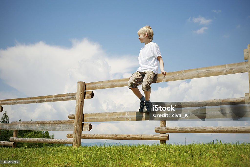 Menino sentado em um muro - Foto de stock de Cerca royalty-free