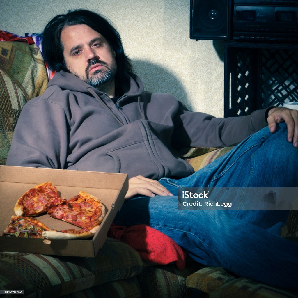 Couch Potato A retro-styled man sitting among a mess on an old couch in a messy room. Messy Stock Photo