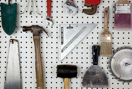 Various tools organized on a white pegboard.