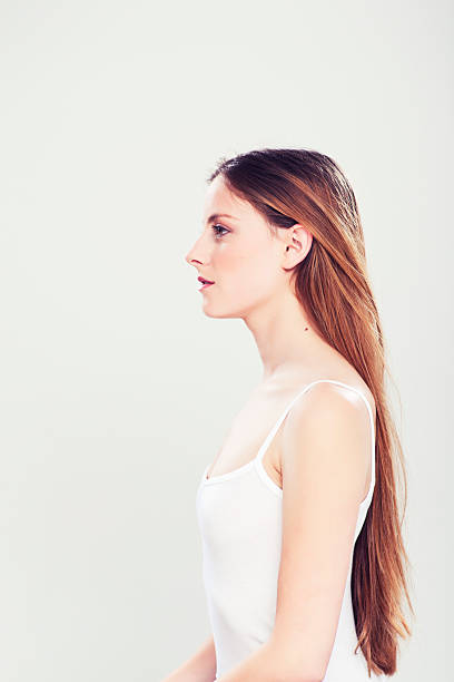 One young woman sitting down at a table, she is in profile and serious. More files of this model and series on port. Made with professional make-up and studio equipment. Cross porcessed image.