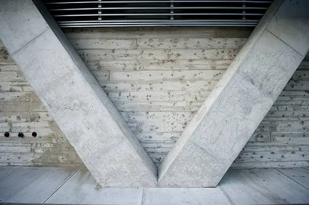Close-up abstract view of concrete bracing forming a v shape against freshly poured concrete wall