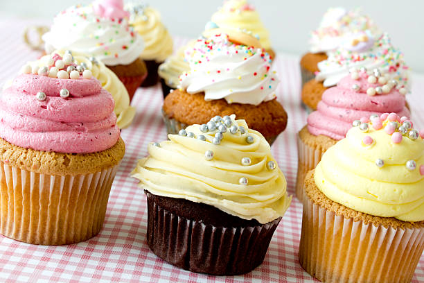 istock Twelve cupcakes with frosting and sprinkles on checker cloth 184300392