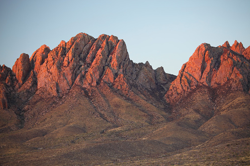 The Organ Mountains are a rugged mountain range in southern New Mexico in the Southwestern United States near Las Cruces. Photo of soft afternoon light on the surrounding desert mountain peaks. The Mountains serve as a haven for one of the most diverse plant and wildlife communities in the Southwest.