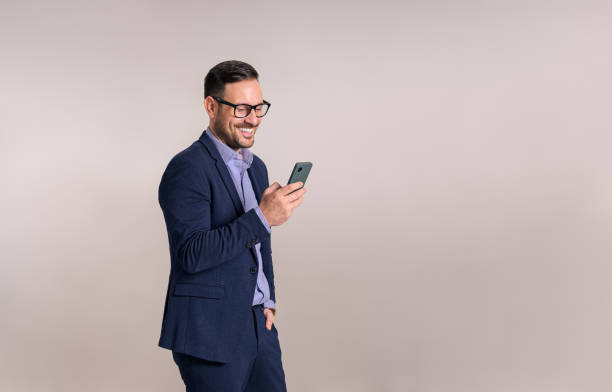 istock Smiling handsome young entrepreneur checking e-mail over mobile phone against white background 1843006394