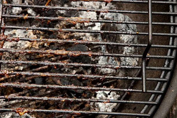 Dirty barbeque grill with charred food particles.