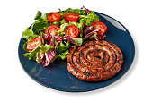 Fried sausage with chopped cherry tomatoes and assorted lettuce leaves isolated on white background