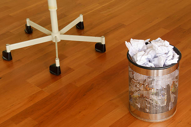 Office chair on hardwood floor with garbage can