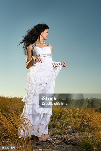 Hermosa Mujer Wearing White Dress De Pie En Un Campo Foto de stock y más banco de imágenes de Cielo