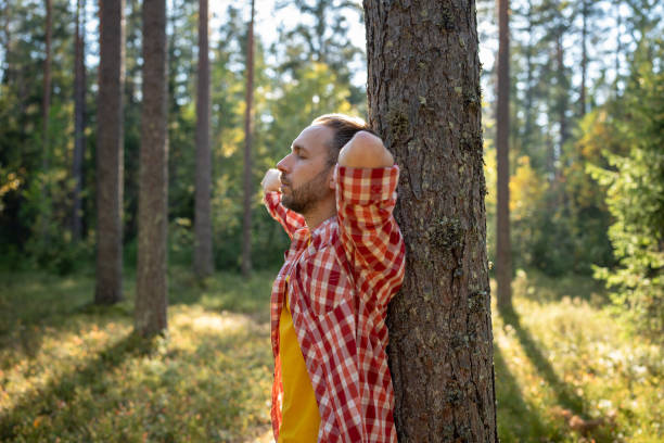istock Relaxed man leans on pine tree meditating standing in forest resting with closed eyes in hike. 1843022208