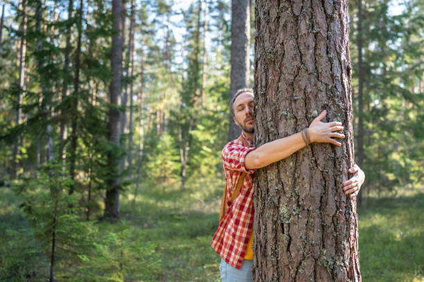 istock Relaxed man hugging cuddling tree trunk on nature in forest with closed eyes protecting environment. 1843022262