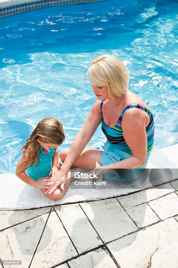 Ragazza con nonna mettendo sulla Crema solare - Foto stock royalty-free di Adulto in età matura