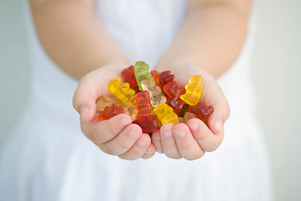 A little girl with a handful of gummy bears Beautiful gummy bears in palms. gummi bears stock pictures, royalty-free photos & images