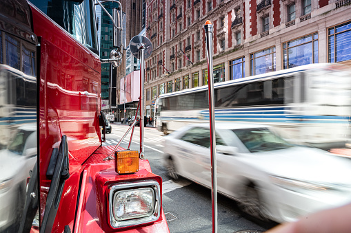 A fast-paced street in Manhattan, New York with a red vintage fire truck in the foreground and blurred moving vehicles in the background showcasing the hustle of the city.