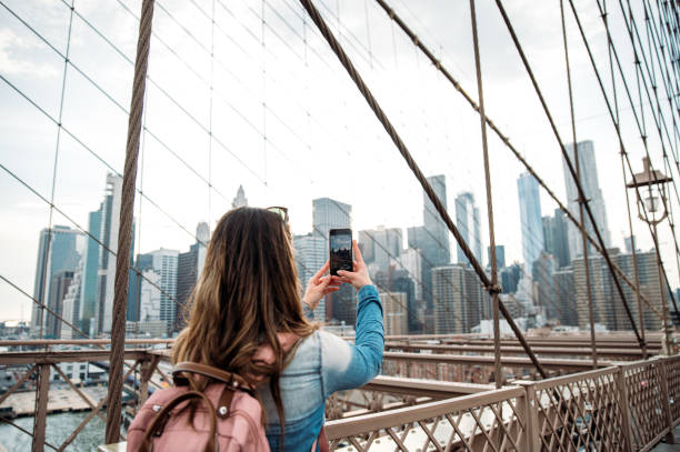 istock Woman capturing Manhattan skyline from Brooklyn Bridge 1843032704
