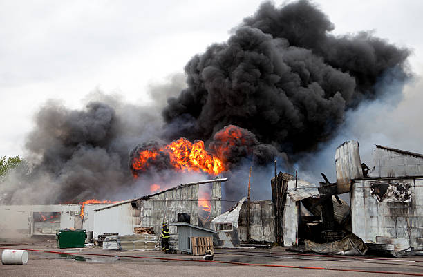 An old warehouse on fire with black smoke  Building engulfed in smoke and fire. fire hose photos stock pictures, royalty-free photos & images