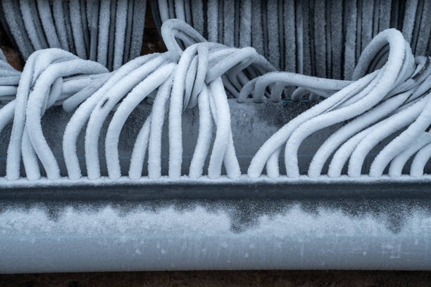 Twisted flexible refrigerated hoses covered with hoarfrost. Engineering system for skating rink cooling filled with frozen water. Preparation and installation of outdoor skating rink for winter