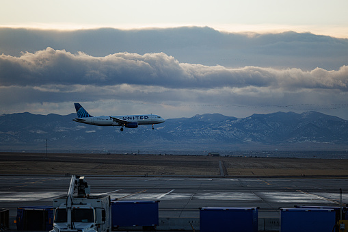 Denver, CO USA - December 4, 2023: United Airlines airplane landing at Denver International Airport on a mostly cloudy winter day.