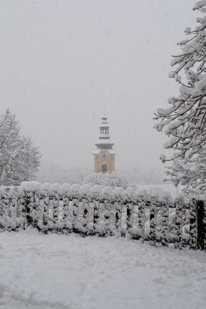istock Clock and spire of a church bell tower under snowfall 1843053949