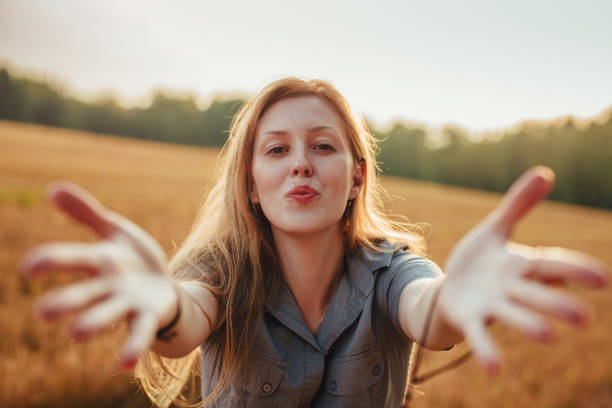 Portrait of young woman in a field, extending arms for an embrac stock photo